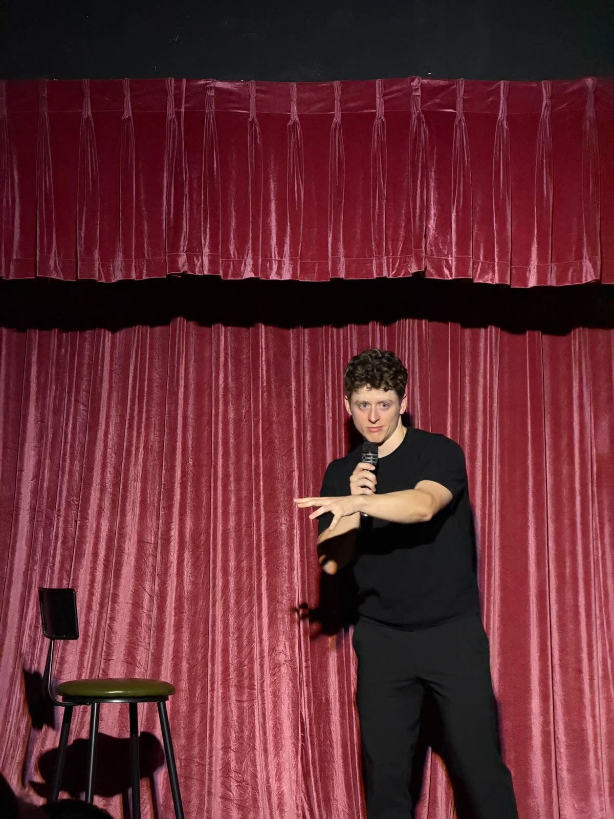 Stephen Vũ mid-bit on stage in front of the red curtain