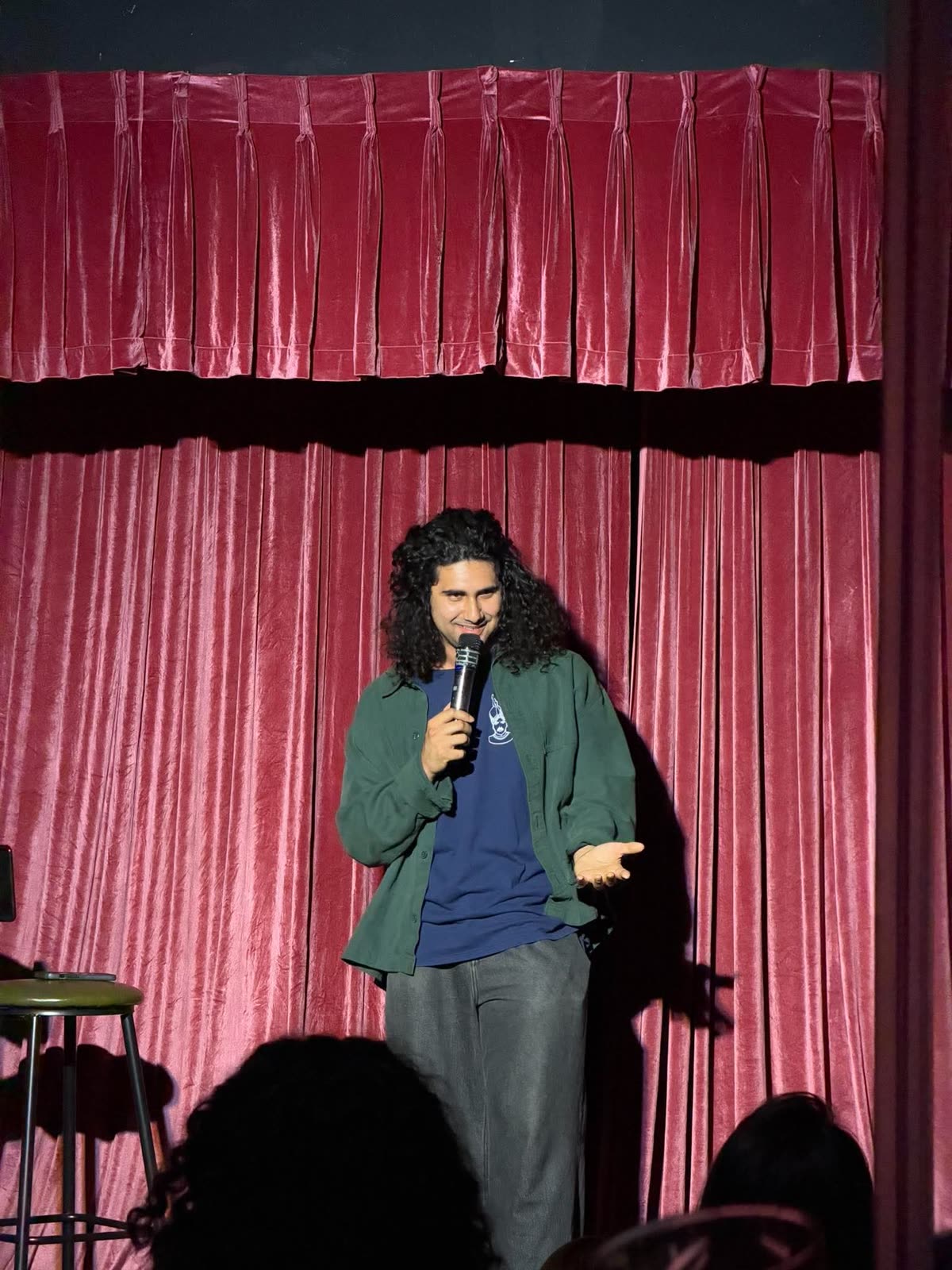 Seth Kelly on stage in a green jacket, holding the mic
